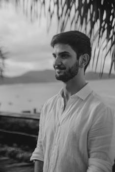 Bearded Man in a Shirt Standing by the Water on an Island